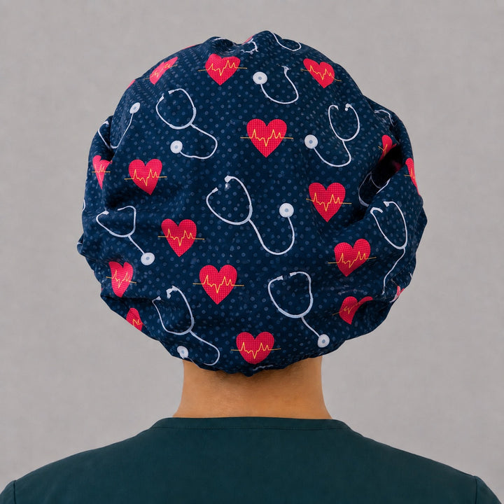 Back view of the cardiology all-over print bouffant scrub cap — red EKG hearts and white stethoscopes across the full navy crown, no contrast band