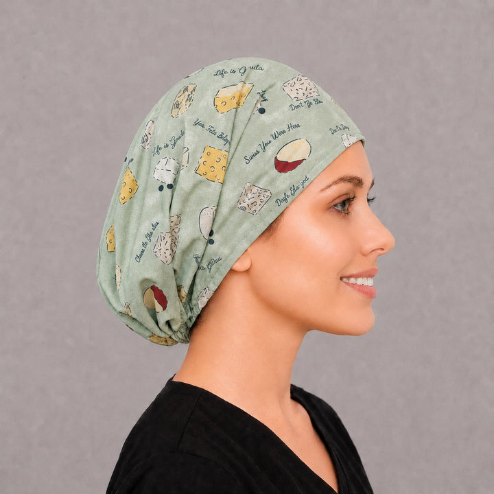 Back view of the cheese Euro scrub cap — full gathered coverage showing cheese wedges and puns across the sage crown