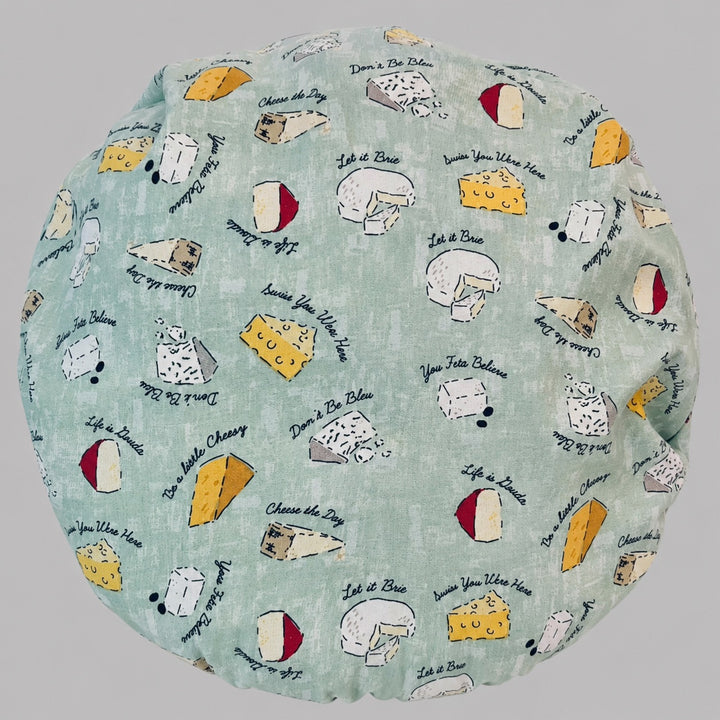 Flat-lay of the cheese print bouffant scrub cap — sage green fabric detail showing Let It Brie, Don&