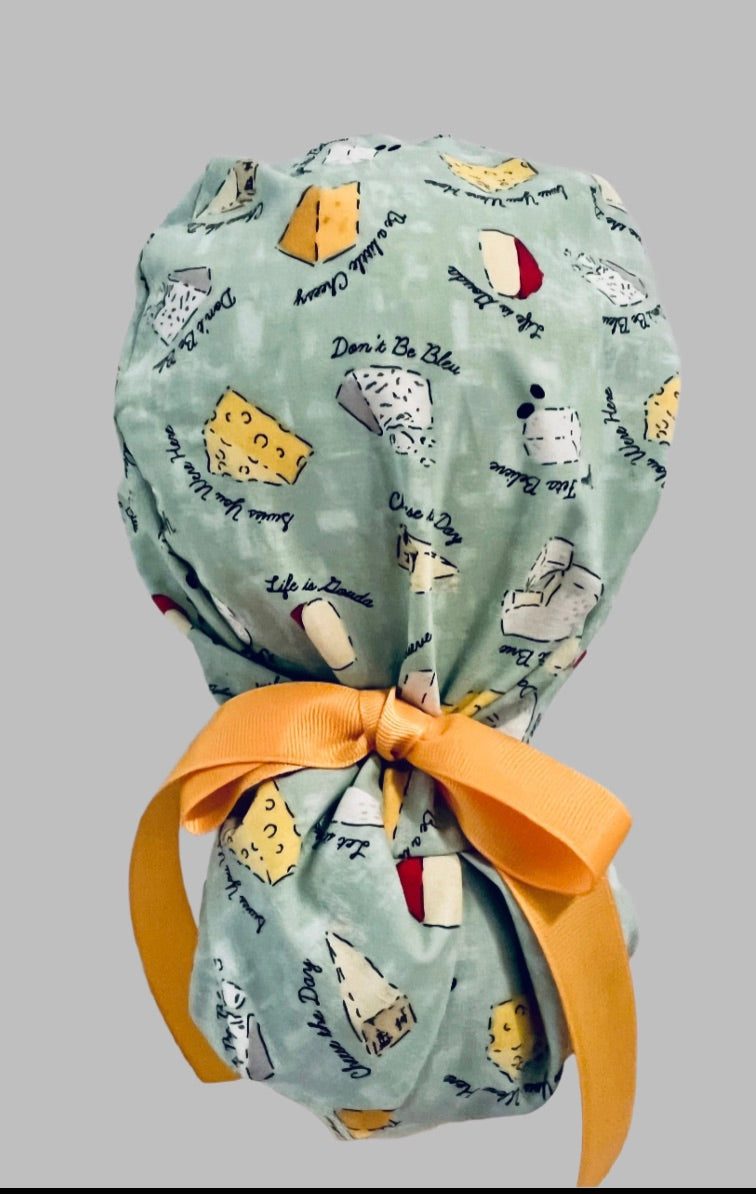 Funny cheese pun ponytail scrub cap back view close-up showing gathered pouch full of cheese wedges, punny sayings and yellow ribbon bow