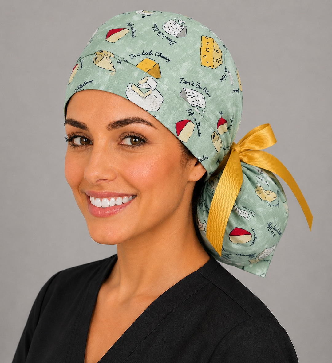 Funny cheese pun ponytail surgical cap left three-quarter angle showing gathered ponytail pouch of cheese illustrations and yellow ribbon bow