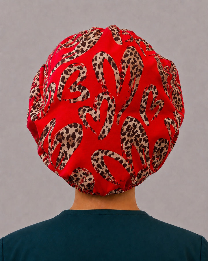 Back view of the cheetah band leopard heart bouffant scrub cap — full gathered fit showing leopard-print hearts across the red crown
