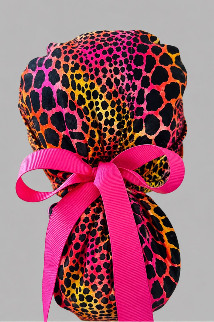 Neon cheetah leopard ponytail surgical cap right three-quarter angle showing gathered ponytail pouch of pink orange yellow leopard print with hot pink ribbon bow