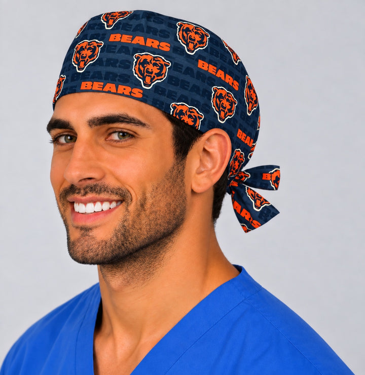 Smiling male nurse in a Chicago football scrub hat, three-quarter angle showing the print scale across the side panel and the tie bow