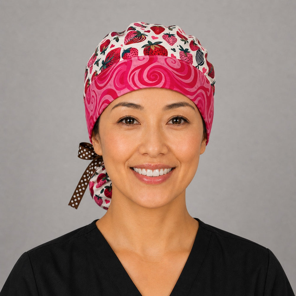 Chocolate-covered strawberry ponytail scrub cap left side profile showing gathered pouch of chocolate-dipped strawberries and hearts with brown polka-dot ribbon tie