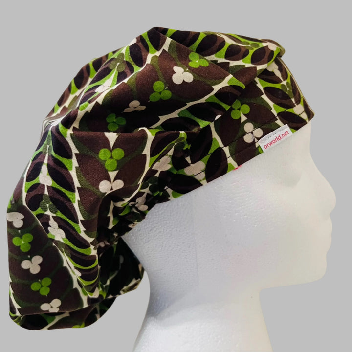 Close-up of retro brown, mint &amp; lime green leaf-and-clover fabric — handmade-in-USA chocolate mint bouffant surgical hat, gift for nurses &amp; surgeons.
