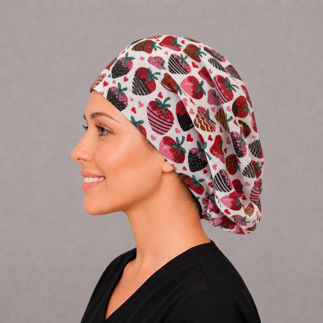 Woman wearing a chocolate-covered strawberry Euro scrub cap, front view — dipped berries and pink hearts on cream, adjustable Valentine&