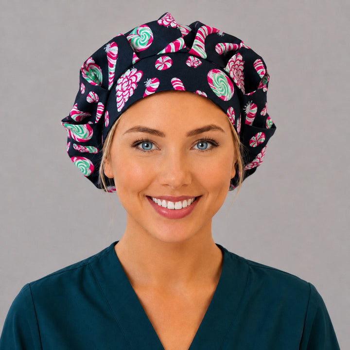 Woman wearing a Christmas candy cane bouffant scrub cap, front view — pink and green peppermints on black, adjustable women&