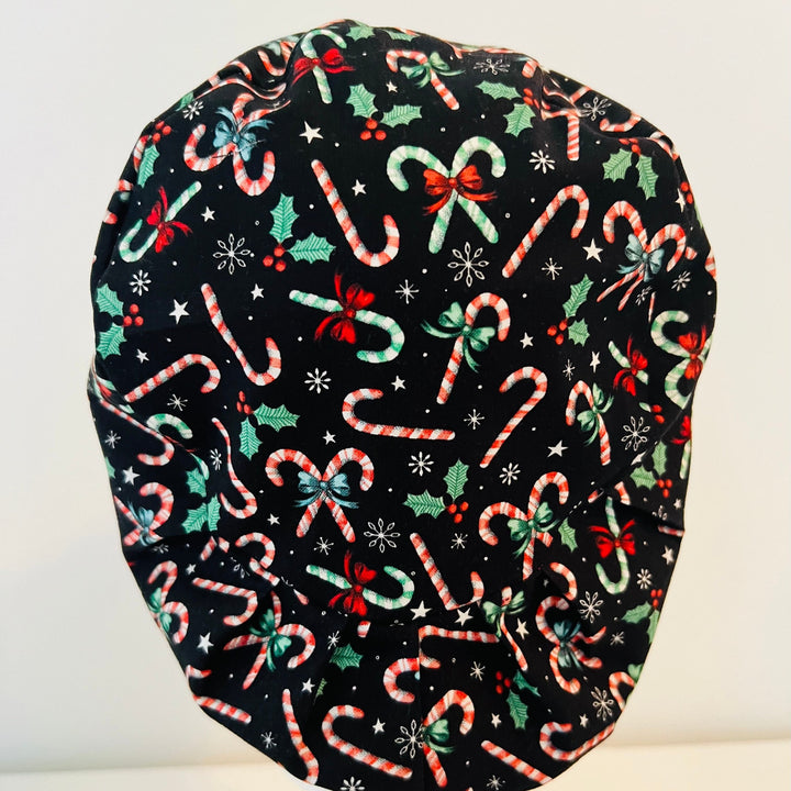 Christmas Candy Cane Euro scrub cap with festive candy canes, holly leaves, bows, stars, and snowflakes on a black background, comfortable surgical cap for nurses, surgeons, doctors, and healthcare professionals, back view.