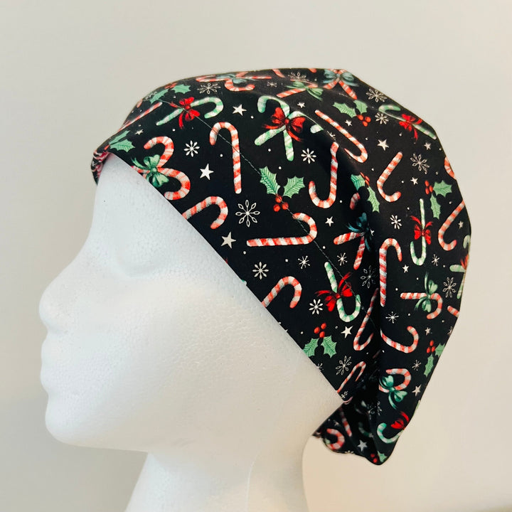 Christmas Candy Cane Euro scrub cap with festive candy canes, holly leaves, bows, stars, and snowflakes on a black background, comfortable surgical cap for nurses, surgeons, doctors, and healthcare professionals, left side view.