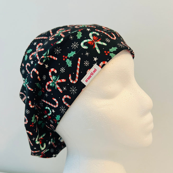 Christmas Candy Cane Euro scrub cap with festive candy canes, holly leaves, bows, stars, and snowflakes on a black background, comfortable surgical cap for nurses, surgeons, doctors, and healthcare professionals, right side view.