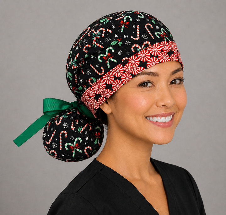 Woman wearing Christmas candy cane peppermint ponytail scrub cap, front view smiling with red white and green candy canes, holly and peppermint swirl band with green ribbon tie