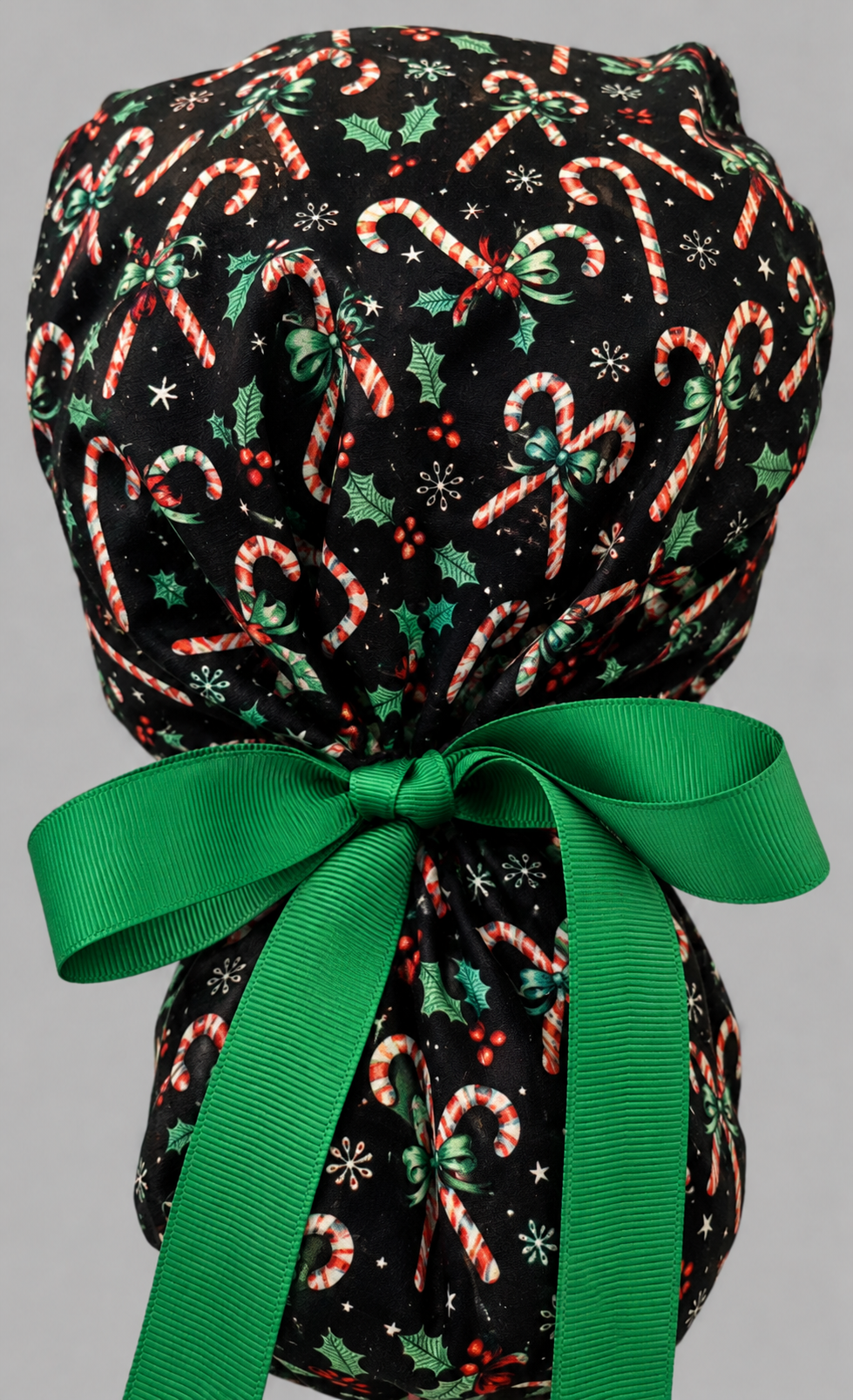 Christmas candy cane peppermint ponytail nurse cap right three-quarter angle on smiling model showing candy canes, holly and peppermint band with green ribbon bow