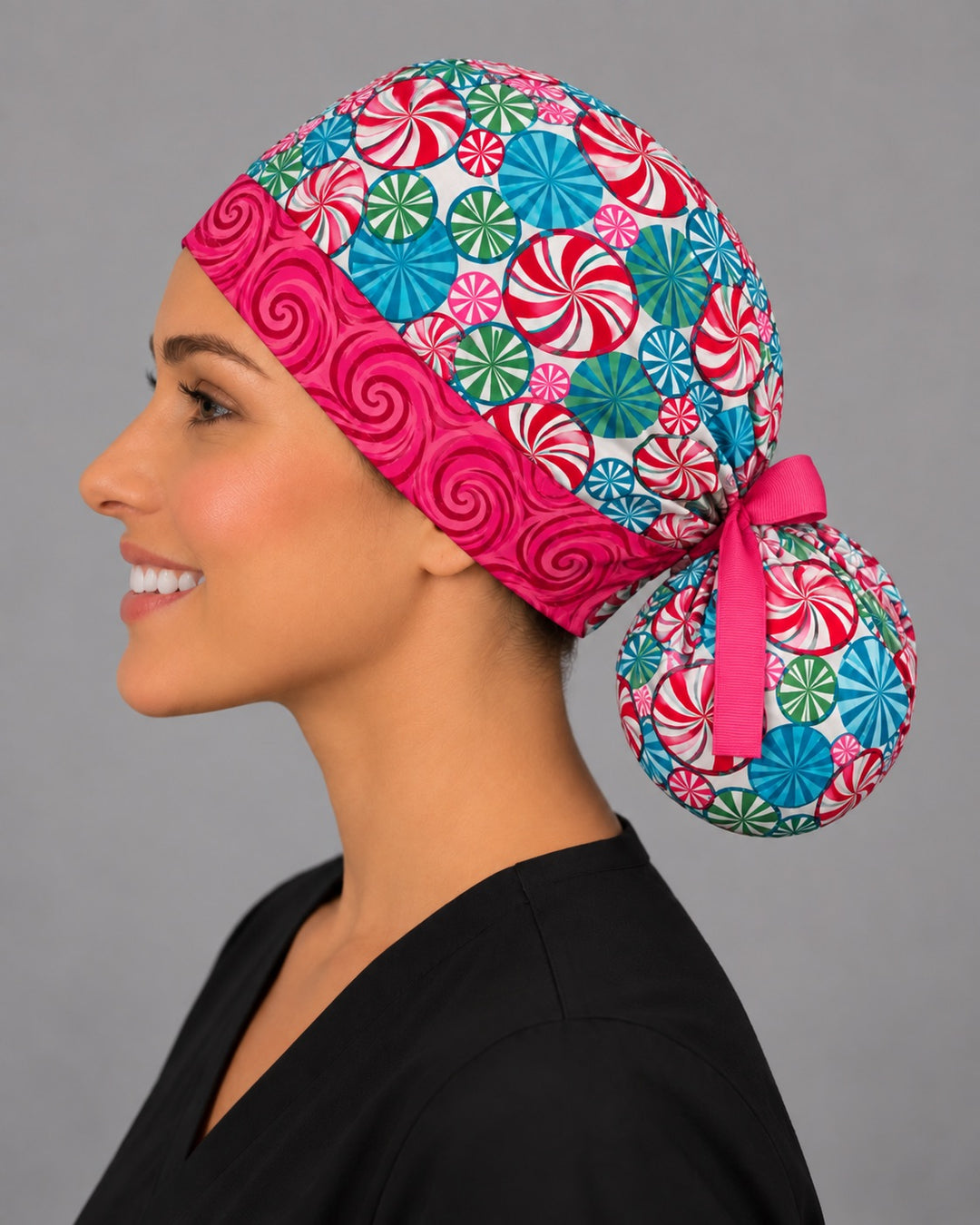 Christmas candy ponytail surgical cap, left side profile — pink swirl front band and roomy bun pouch, handmade in the USA