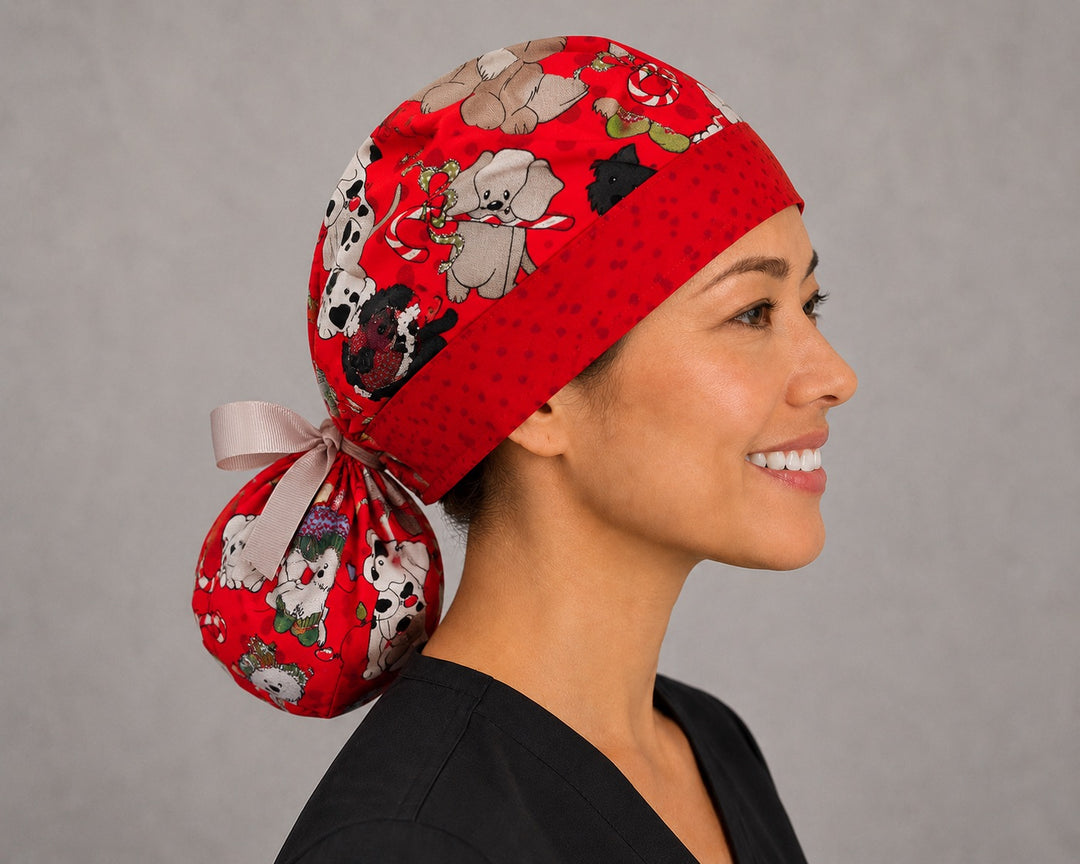 Christmas dogs ponytail surgical cap right three-quarter angle showing pups in Santa hats and sweaters on red with red polka-dot band and white ribbon bow