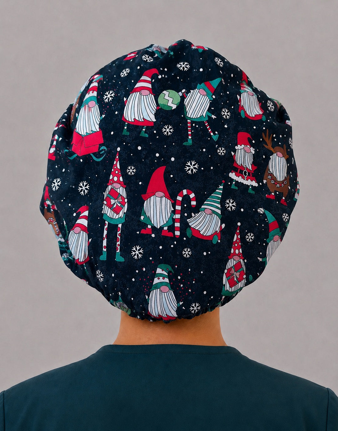 Woman wearing a Christmas gnome bouffant scrub cap, front view — navy gnome print with red, green and white snowflake band, adjustable women&