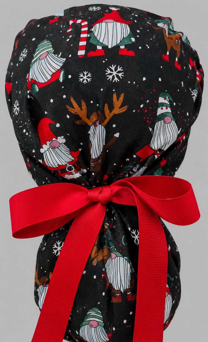Christmas gnomes ponytail scrub cap left side profile showing gathered pouch of holiday gnomes, ornaments and snowflakes on black with red ribbon tie