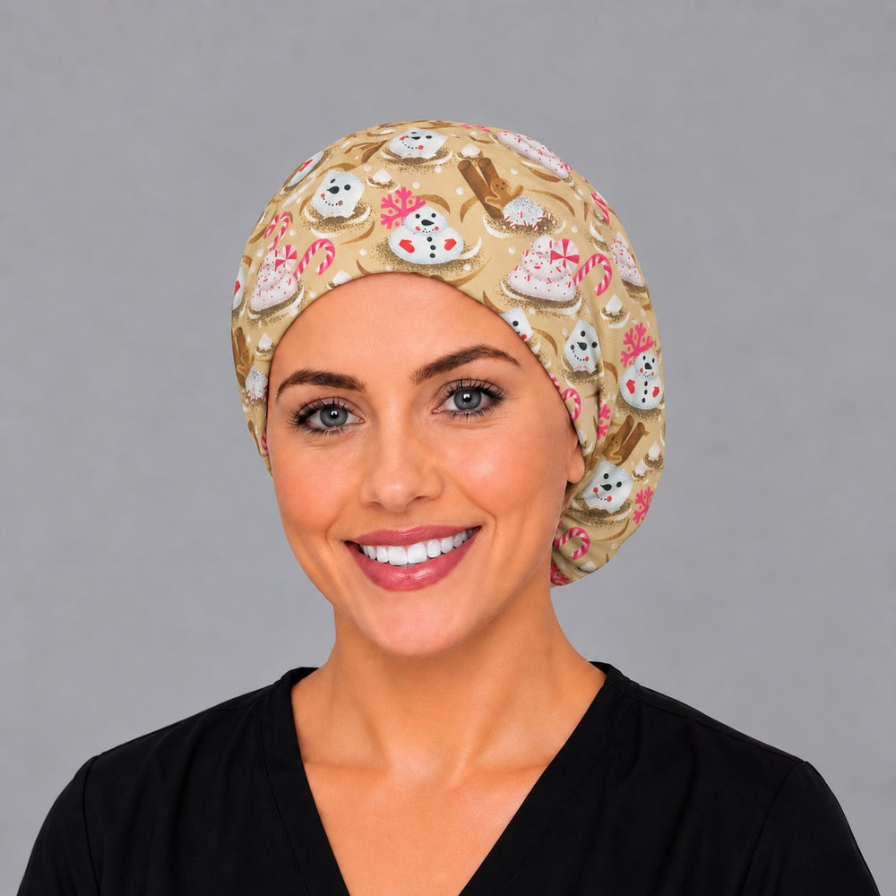 Woman wearing a Christmas marshmallow Euro scrub cap, front view — snowman marshmallows and candy canes on gold, adjustable surgical hat