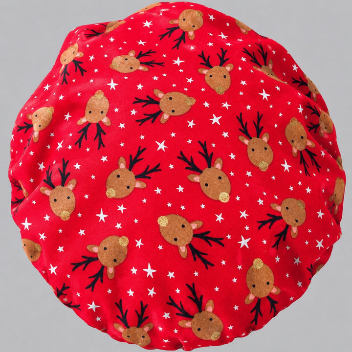 Flat-lay of the Christmas reindeer bouffant scrub cap — red fabric detail showing reindeer with black antlers, gold noses and white stars