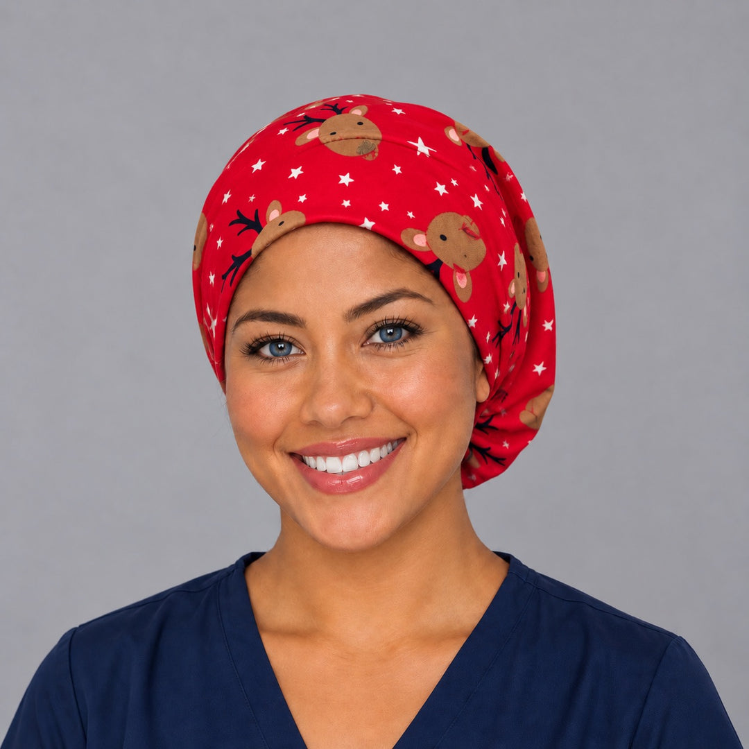Woman wearing a Christmas reindeer Euro scrub cap, front view — reindeer faces and white stars on cherry red, adjustable holiday surgical hat