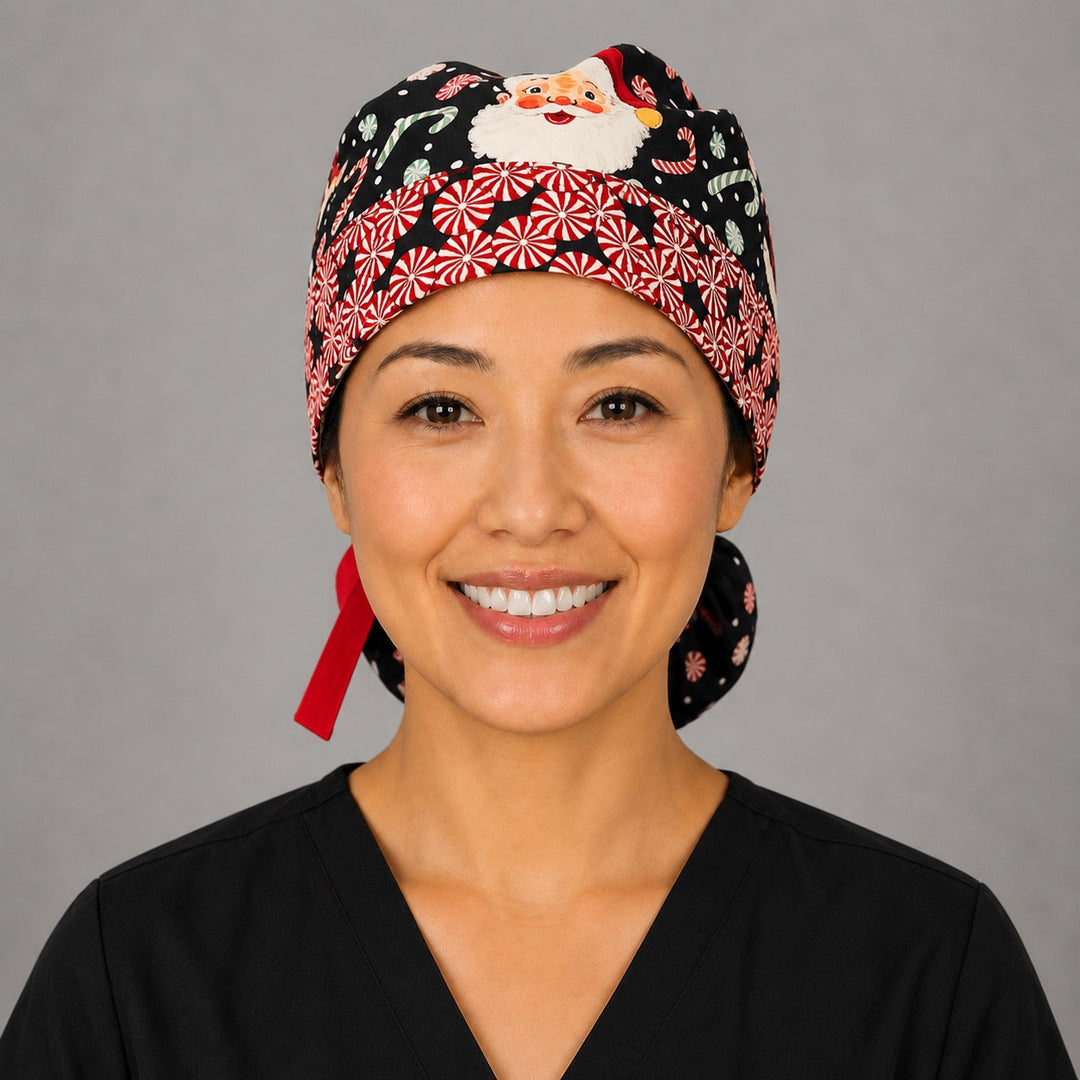 Christmas Santa ponytail scrub cap front band close-up on smiling model showing red-and-white peppermint band with vintage Santa faces on navy and red ribbon