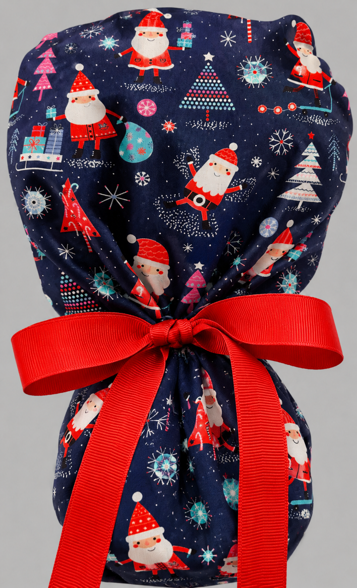Christmas Santa ponytail nurse cap left three-quarter angle on smiling model showing Santas, Christmas trees, presents and snowflakes on navy blue with red ribbon bow