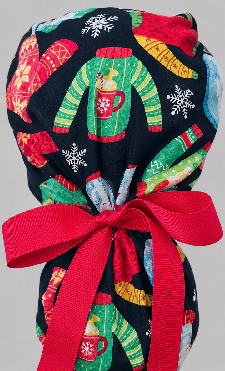 Christmas ugly sweater ponytail scrub cap back view close-up showing gathered pouch full of festive knit sweaters, mittens and snowflakes on black with red grosgrain ribbon bow