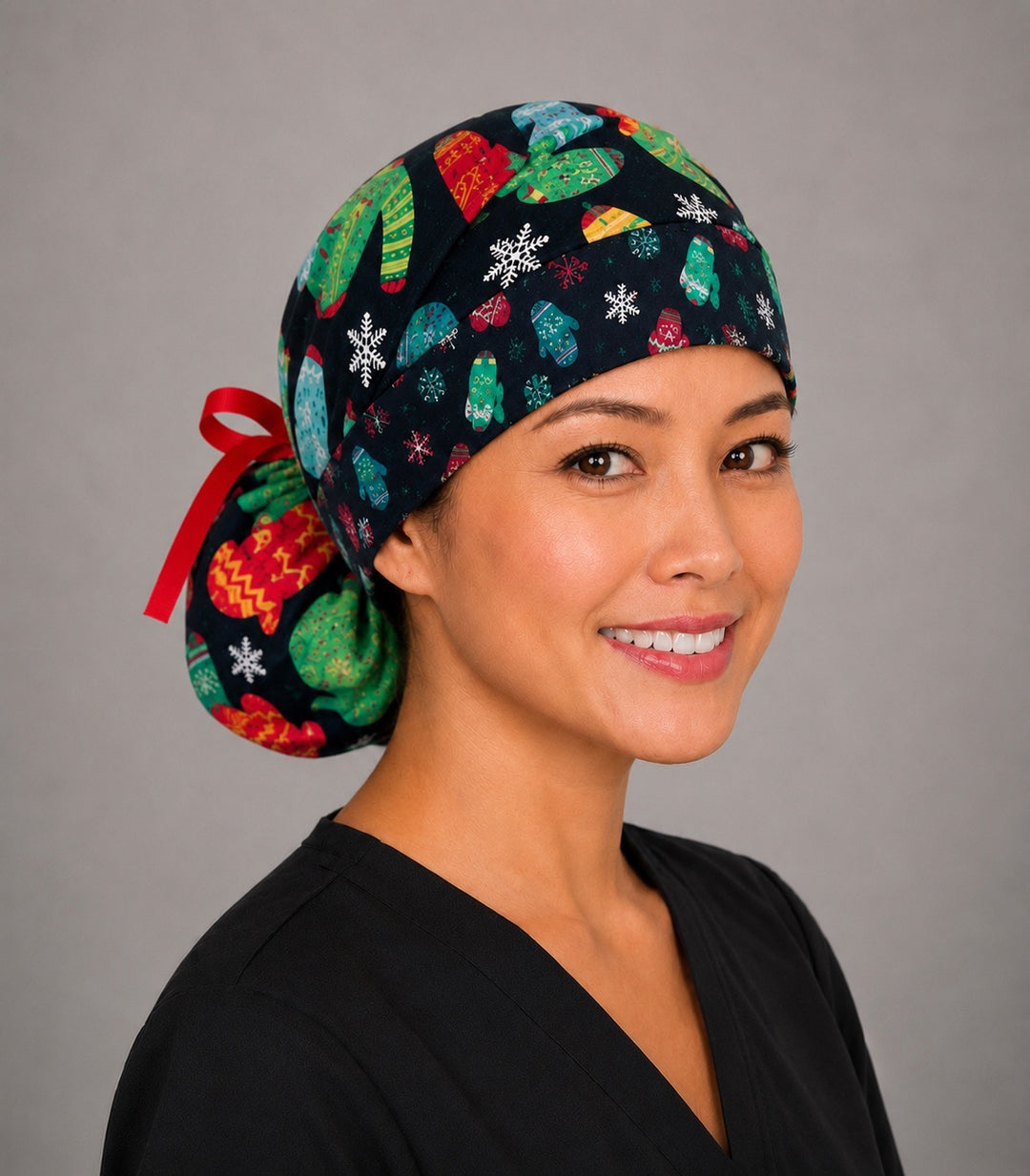 Christmas ugly sweater ponytail scrub cap right side profile with full ponytail pouch of knit sweaters, mittens and snowflakes on black and long red ribbon ties