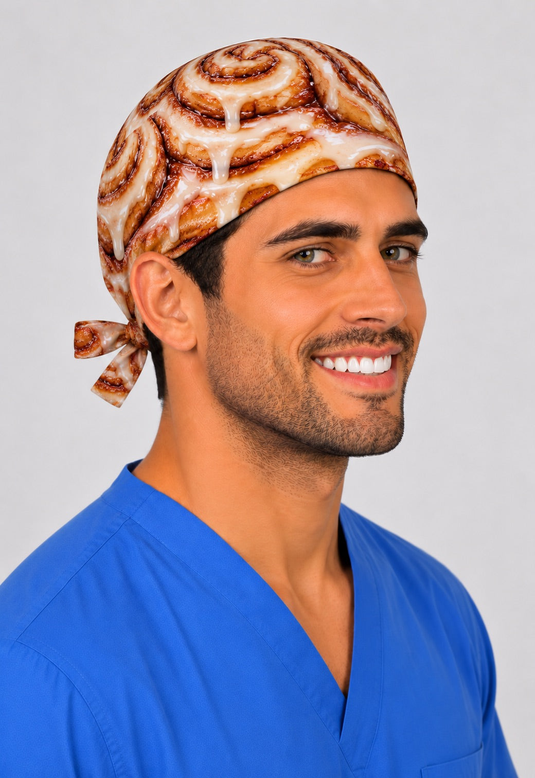 Smiling male nurse in a photorealistic cinnamon roll tie-back scrub cap with glazed icing swirls