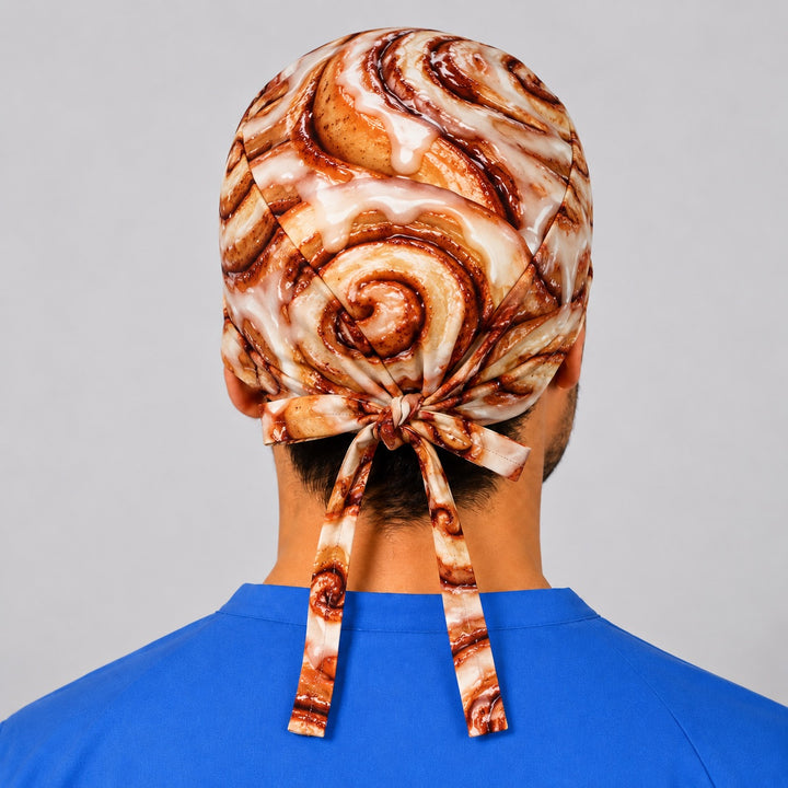 Back of a cinnamon roll tie-back scrub cap showing the swirl crown and long adjustable ties