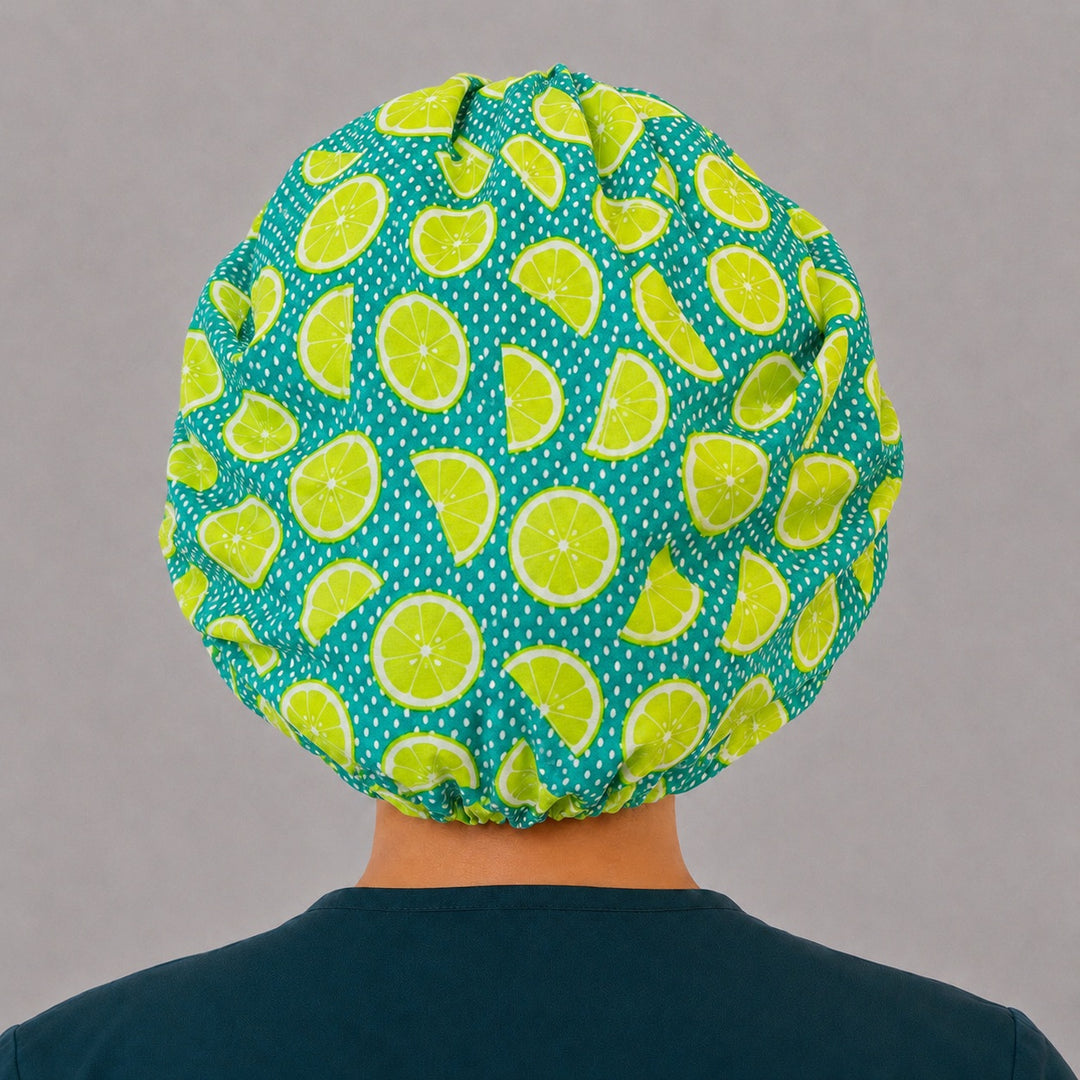 Back view of the citrus bouffant scrub cap showing the full roomy fit and elastic gathered back — lemon lime slices on teal with white dots
