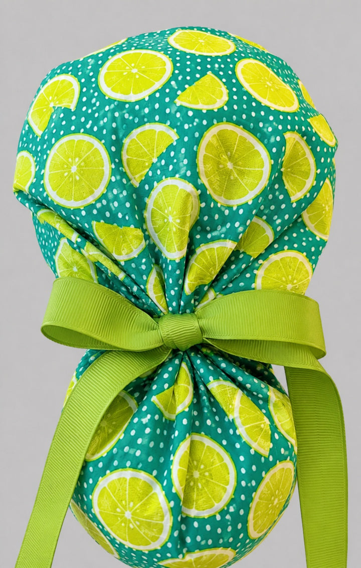 Citrus lemon lime ponytail scrub cap back view close-up showing gathered pouch of yellow and green citrus slices on teal and lime green ribbon bow