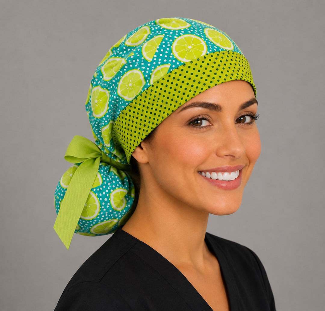 Citrus lemon lime ponytail scrub cap left three-quarter angle showing full ponytail pouch of lime slices on teal and lime green ribbon bow