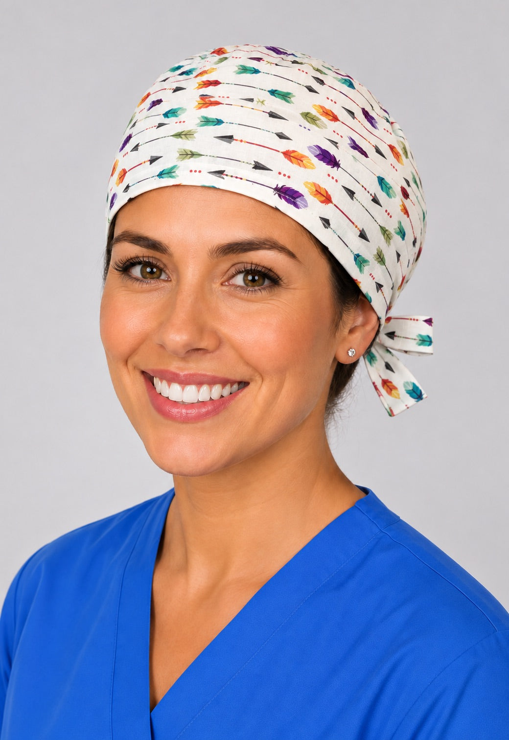 Nurse wearing colorful arrow and feather tie back scrub cap, white boho surgical hat with side tie by OR World