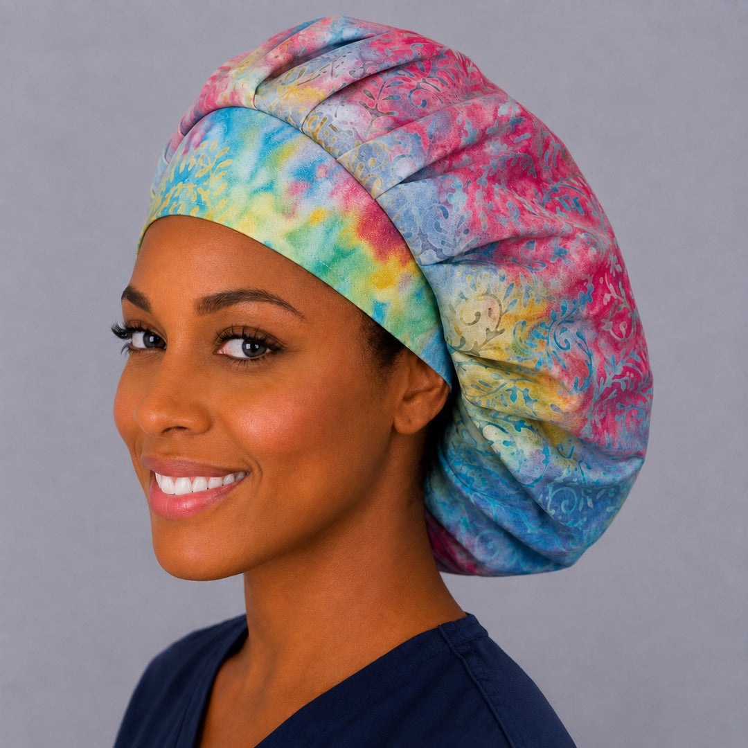 Colorful batik bouffant surgical cap on a smiling nurse, right angled view — bright spring and summer print for OR and L&D teams