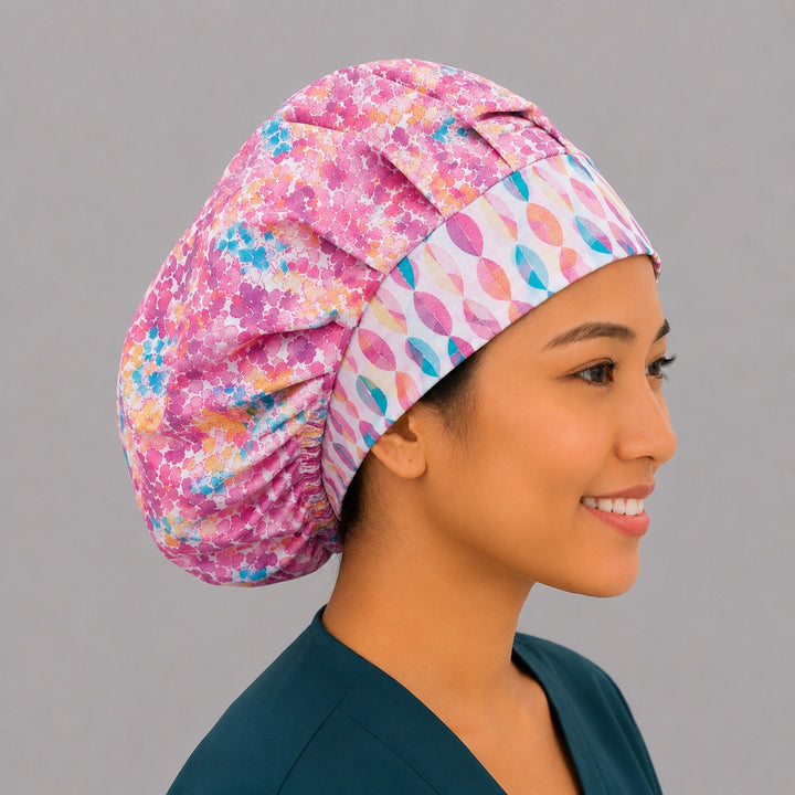 Colorful floral watercolor bouffant surgical cap right three-quarter angle on smiling model showing pink teal orange florals with geometric band, OR World nurse hat