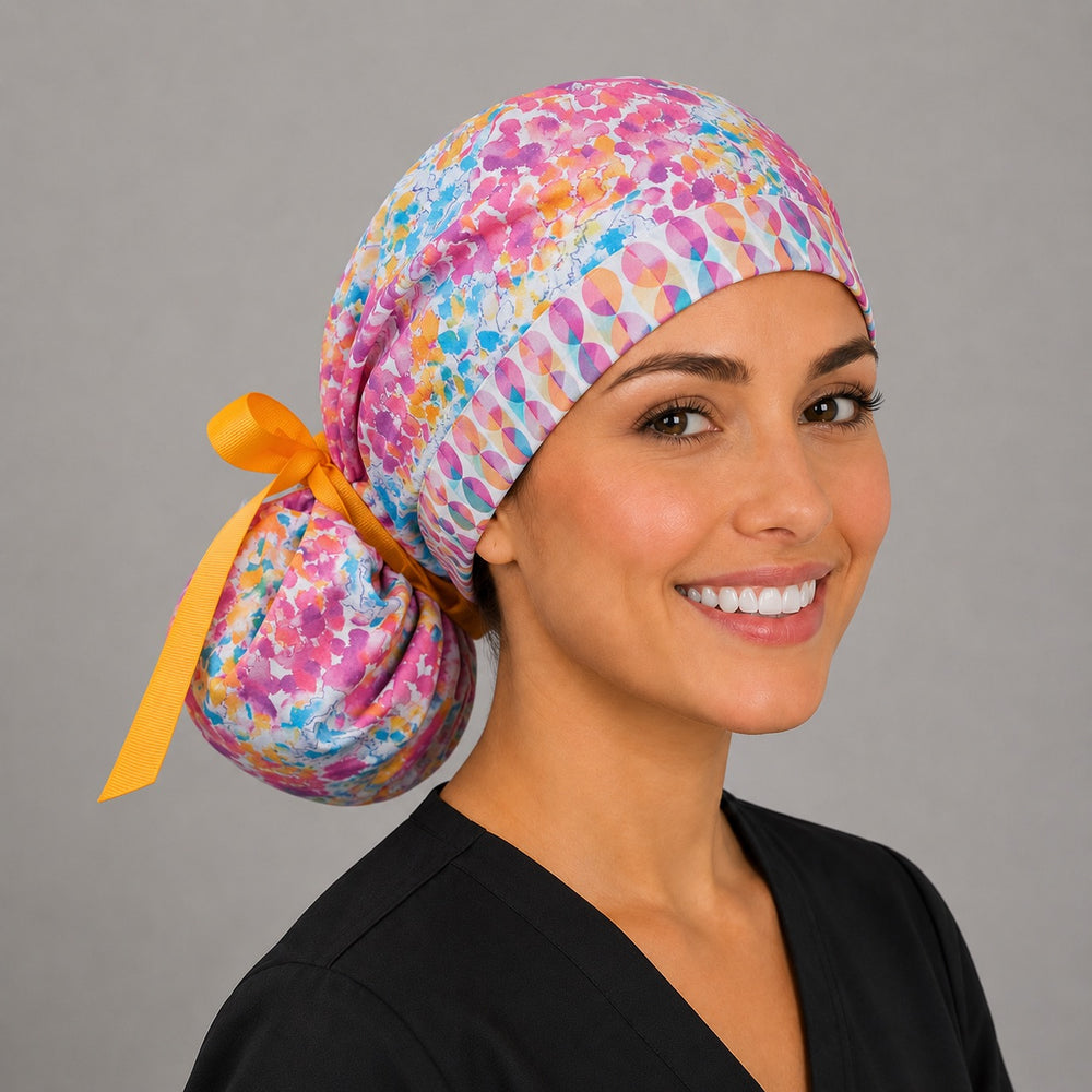 Colorful floral watercolor ponytail scrub cap left side profile with full ponytail pouch of pink teal orange watercolor florals and long gold ribbon ties