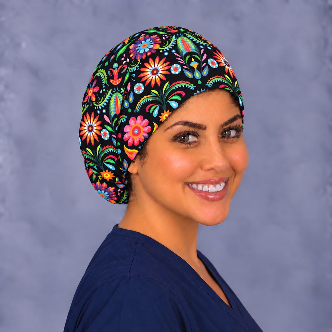 Three-quarter view of a colorful Mexican flower euro OR cap, with soft pleats across the crown and golden heart motifs on the side panel