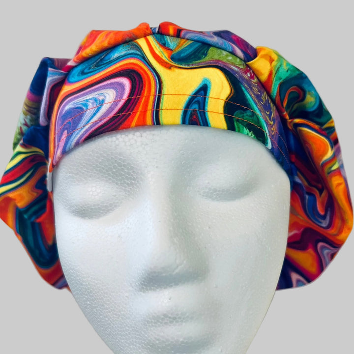 Colorful ripples bouffant scrub cap in swirling rainbow marble print, front view on a model — handmade-in-USA surgical hat for women from OR World.