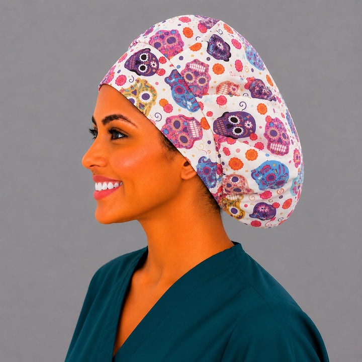 Colorful sugar skull bouffant scrub cap left three-quarter angle on smiling model showing pink purple and blue Day of the Dead skulls, women&