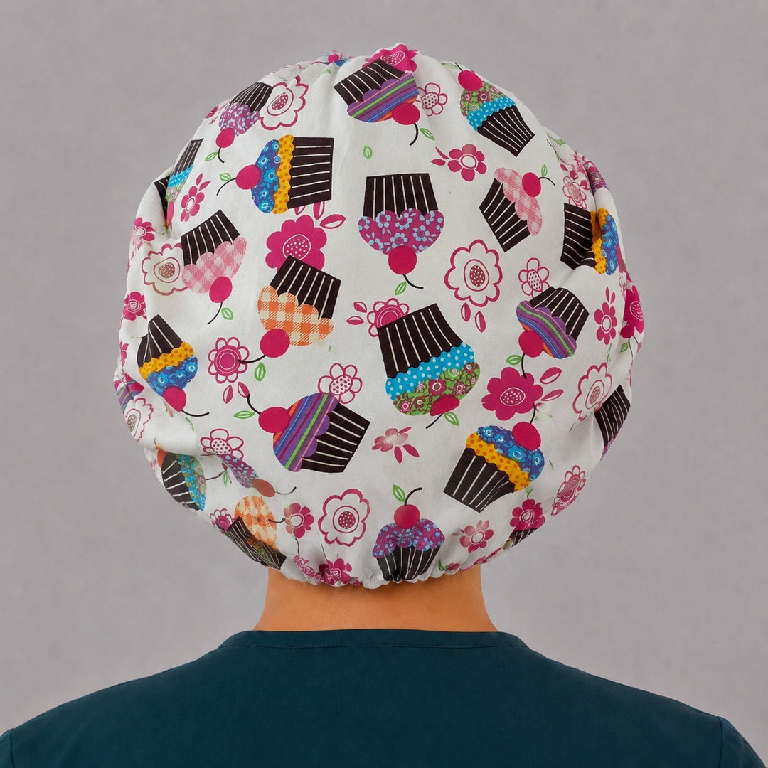 Back view of the cupcake bouffant scrub cap — full roomy fit showing retro cupcakes, cherries and pink flowers on cream