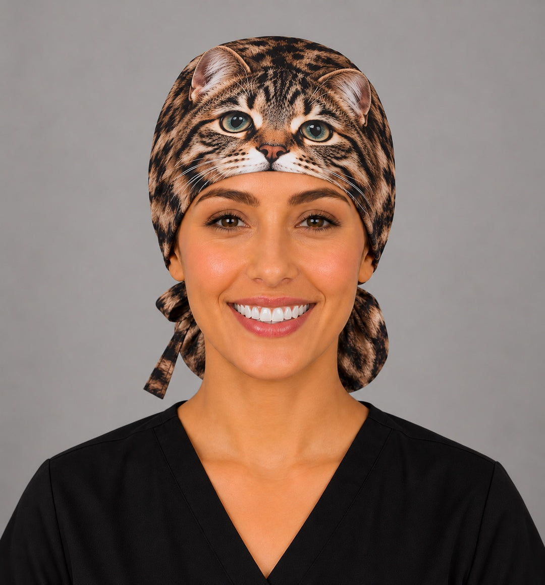 Front view of a custom cat portrait ponytail surgical hat with green eyes and whiskers centered on the band, a unique gift for vet techs and anesthesia