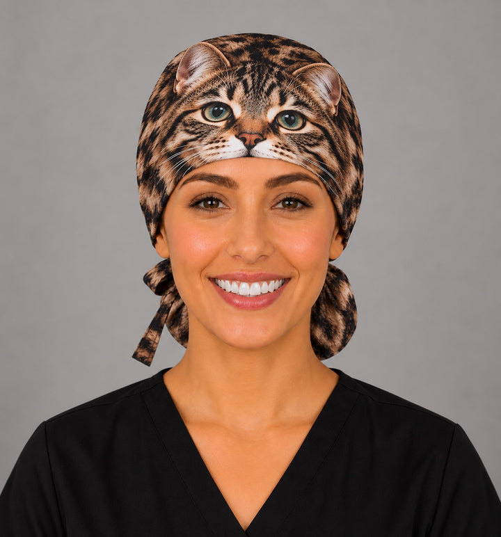 Front view of a custom cat portrait ponytail surgical hat with green eyes and whiskers centered on the band, a unique gift for vet techs and anesthesia