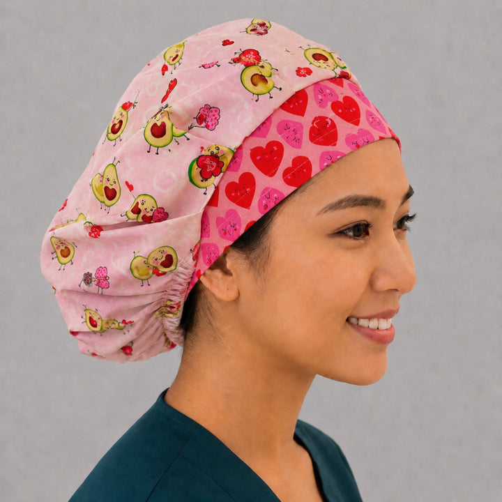 Side view of the cute avocado hearts bouffant surgical hat — blush pink avocado print with pink and red heart contrast band, roomy cotton cap for nurses