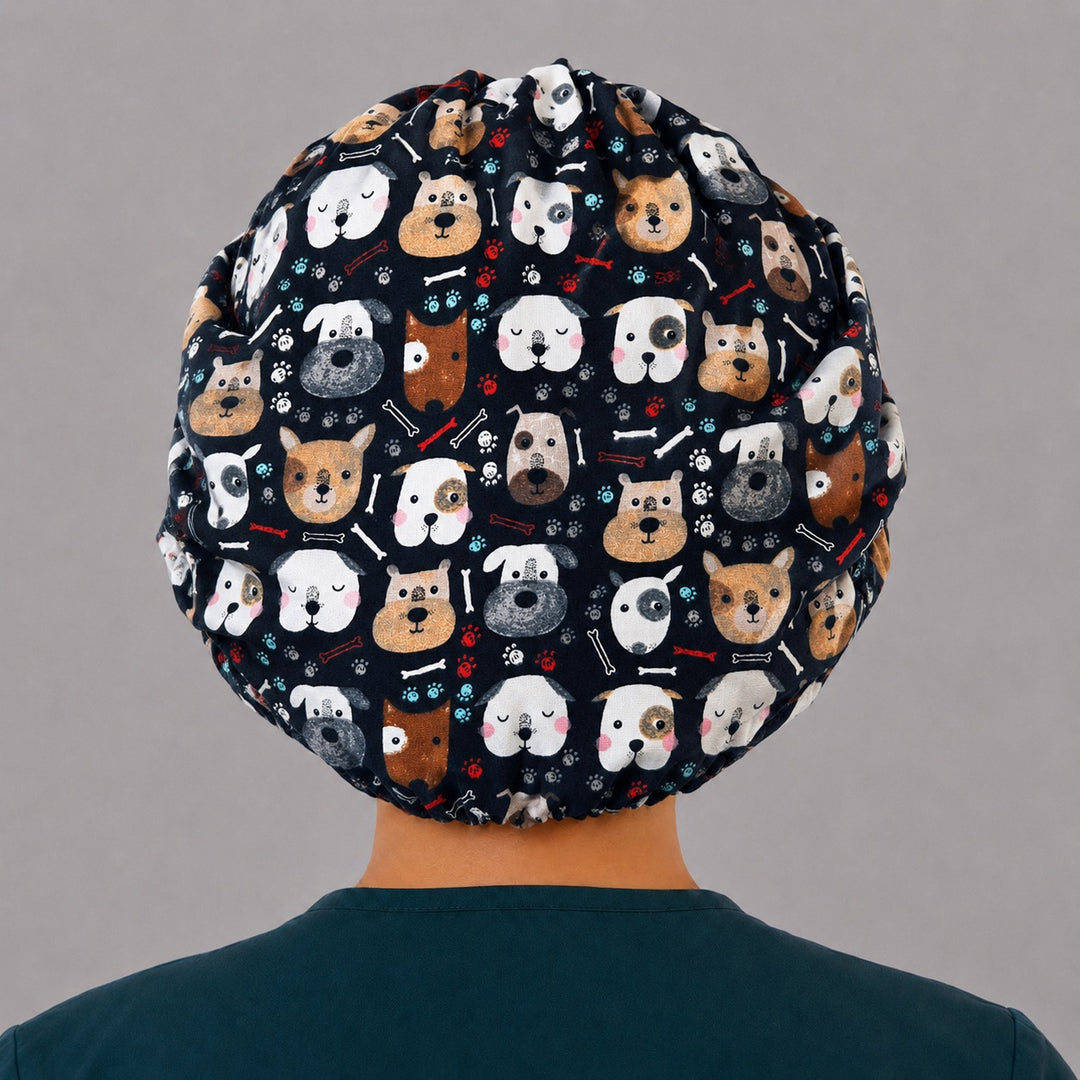 Back view of the cute dog bouffant scrub cap — full roomy fit showing navy puppy faces, bones and paw prints with elastic gather