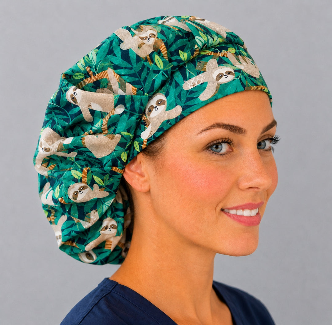 Cute sloth bouffant scrub cap left three-quarter angle on smiling model showing sloths in green tropical jungle leaves, women&