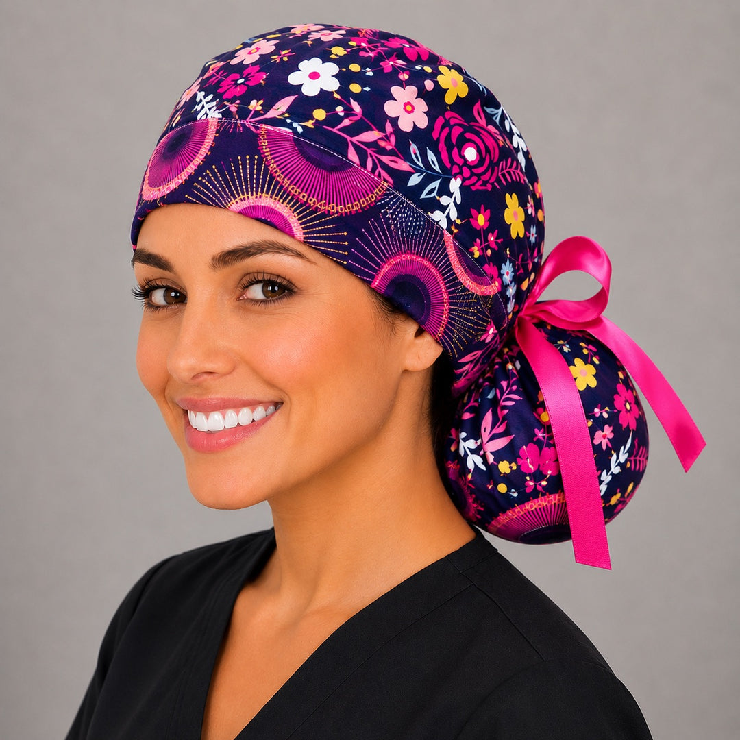 Dark brown floral ponytail scrub cap back view on stand showing gathered pouch of pink, yellow and white flowers on dark brown with pink ribbon bow