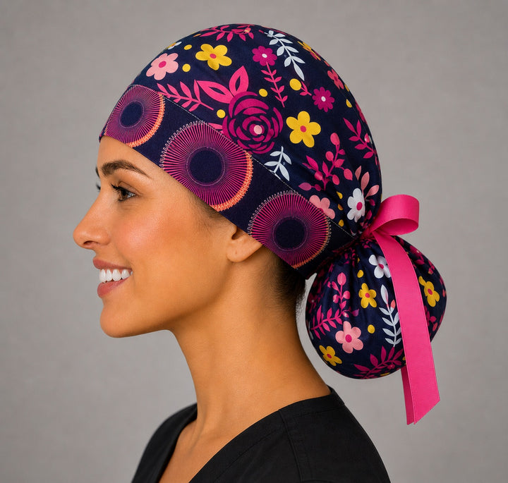 Dark brown floral ponytail scrub cap left side profile with full ponytail pouch of pink, yellow and white flowers and long pink ribbon ties