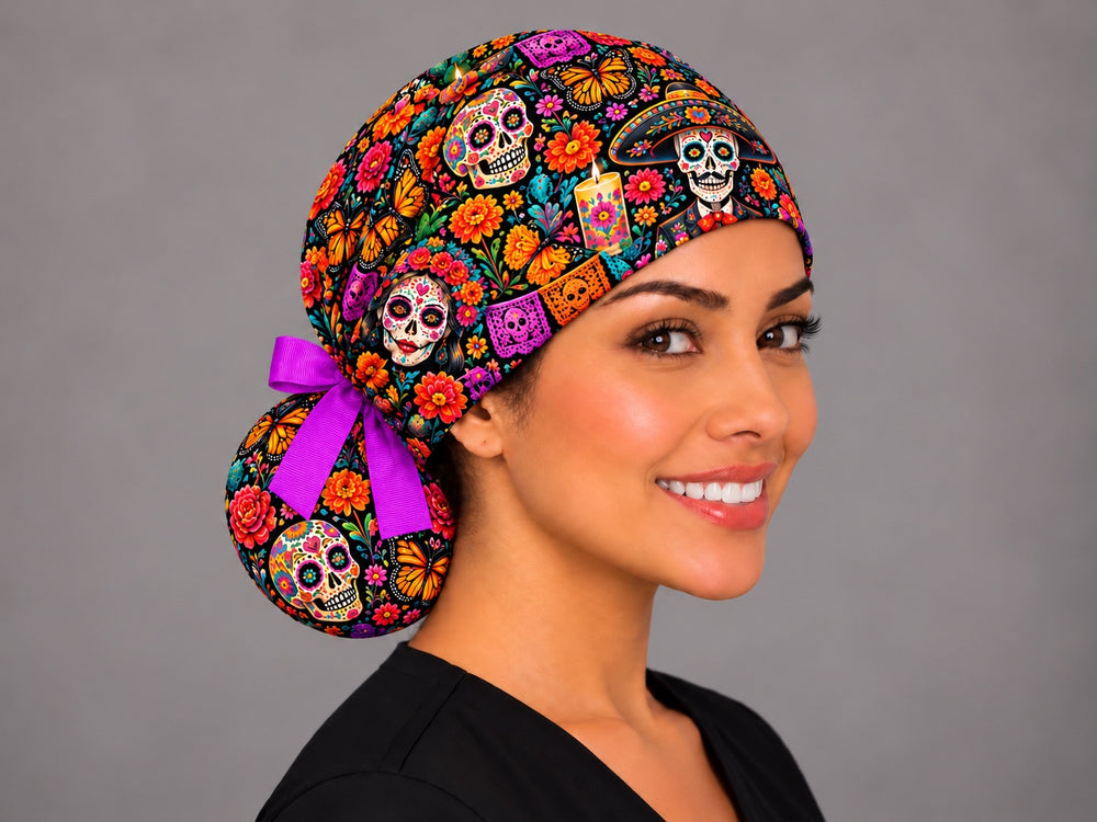 Right angle view of a Day of the Dead ponytail cap showing a sugar skull and marigolds on the round bun tied with a fuchsia ribbon