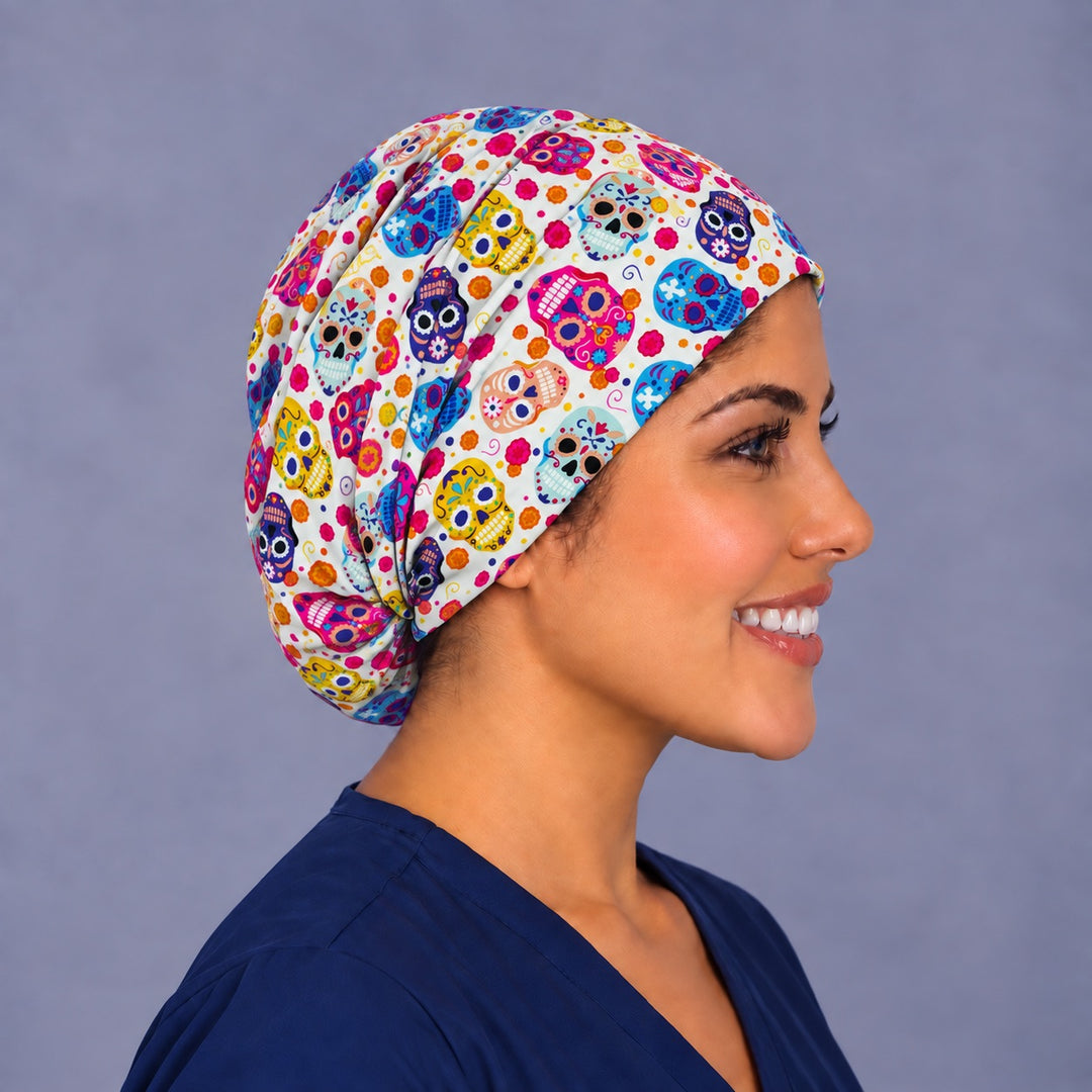 Right side profile of a Day of the Dead surgical cap, with hot pink and sky blue sugar skulls along the side and the elastic gathered behind the ear